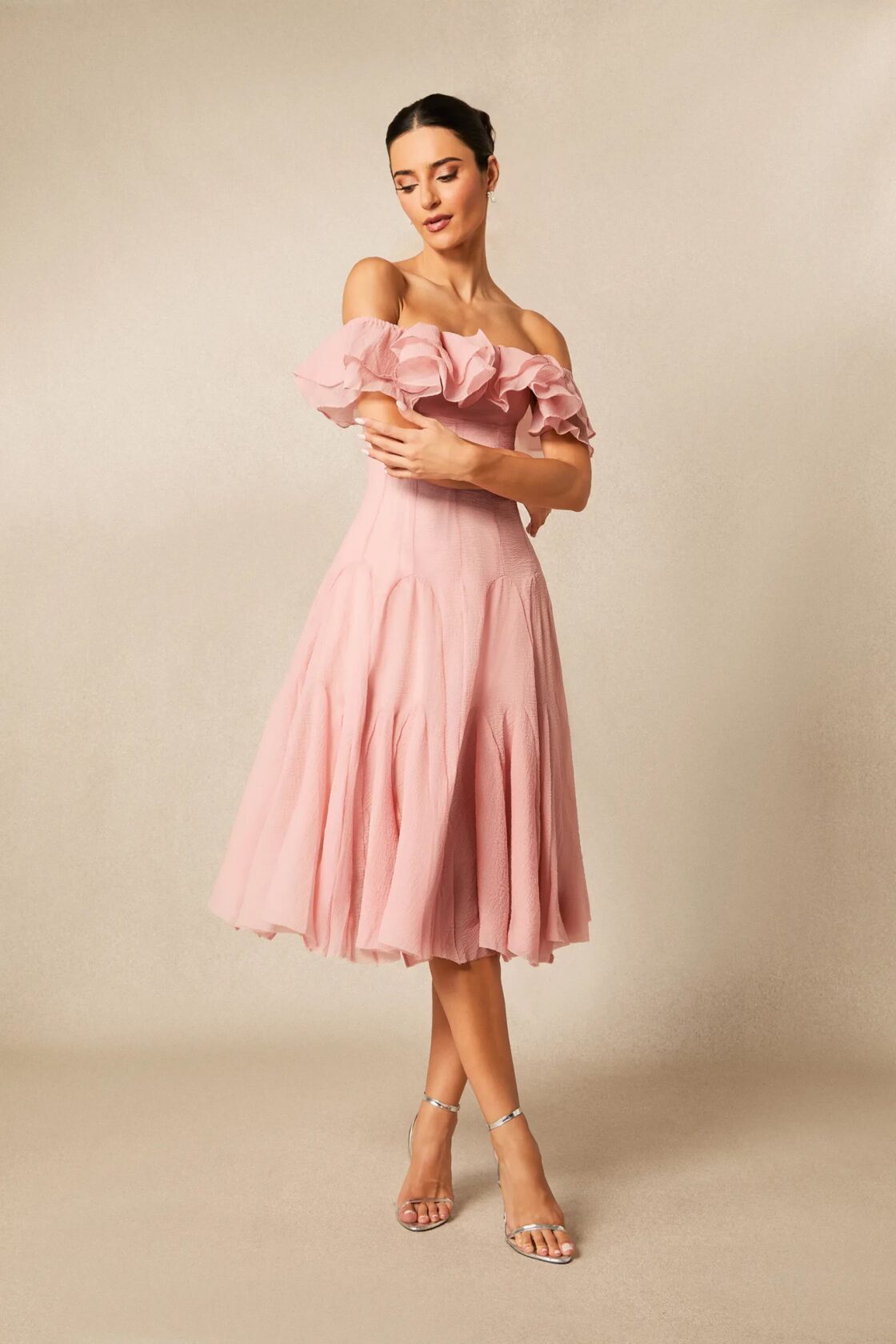 Robe mi-longue rose poudré à manches ballon, plissé souple, sur fond taupe
